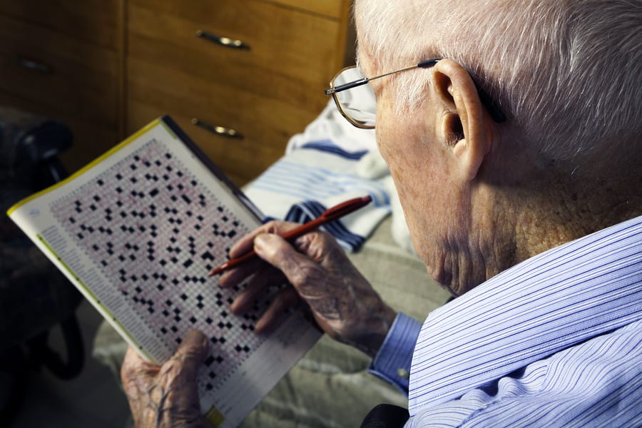 A elderly man doing crossword for brain health