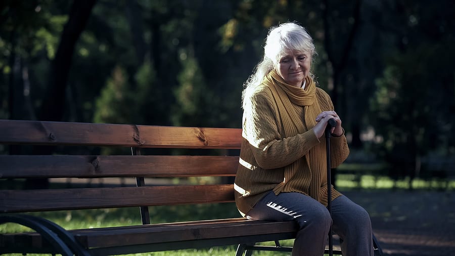 Elderly spouse lonely on bench after death of husband
