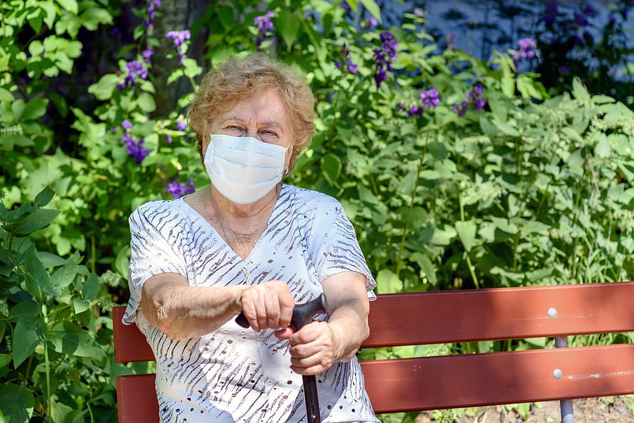 elderly woman in mask sitting in park after exercise walk