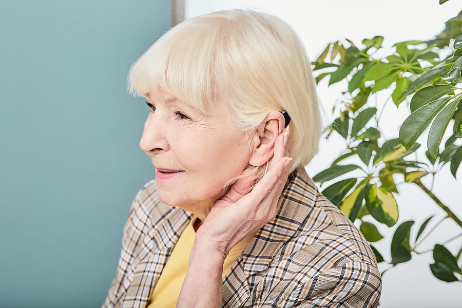 Elderly woman with external hearing aid - hearing loss concept