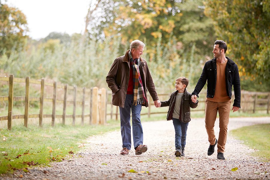 autumnal walk for 3 generations of a family. grandfather walks with son ands grandson