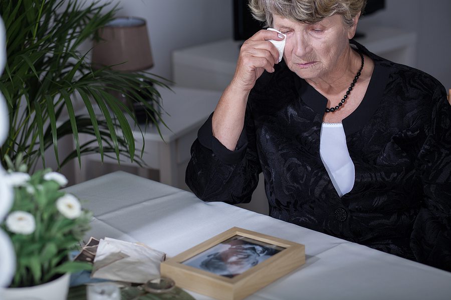 Elderly Woman crying over framed photo, surviving spose concept