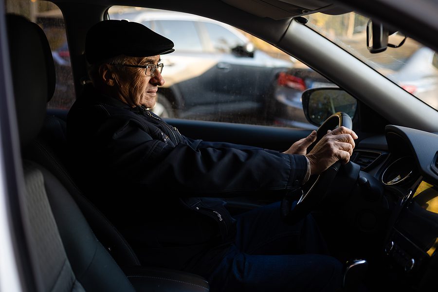 elderly car keys discussion concept - elderly man with glasses sitting in the driver's seat