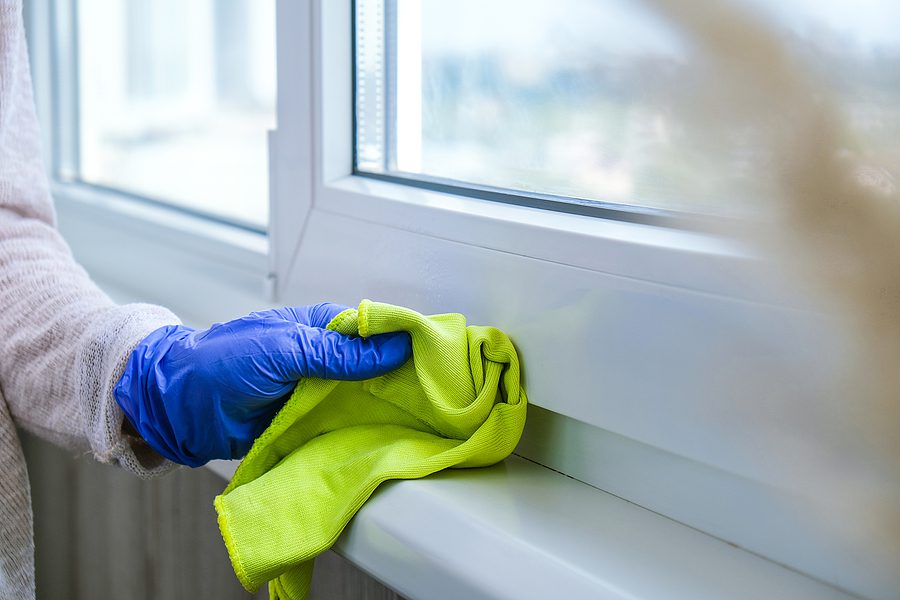 Spring Cleaning Concept - hand in glove wiping a windowsill