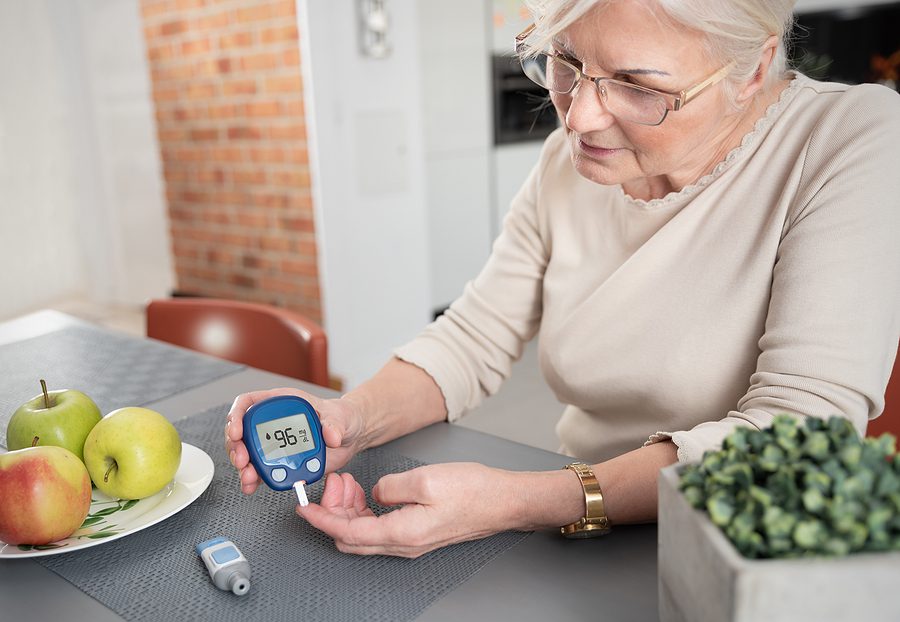 Senior woman with glucometer checking blood sugar level at home. Type 2 Diabetes, health care concept