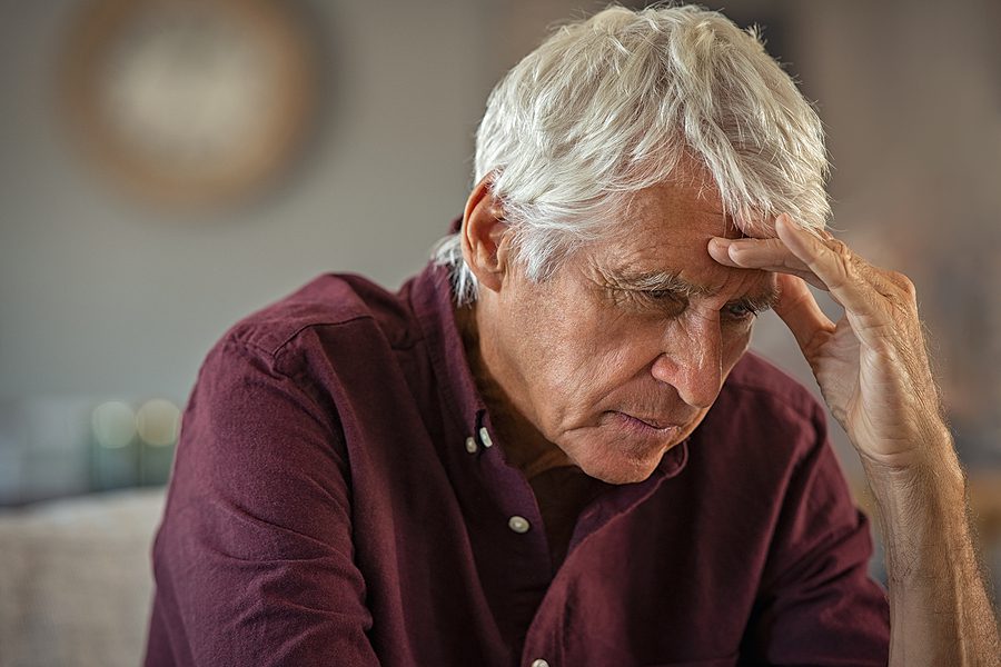 sressed elderly man holds head - anxiety in seniors concept