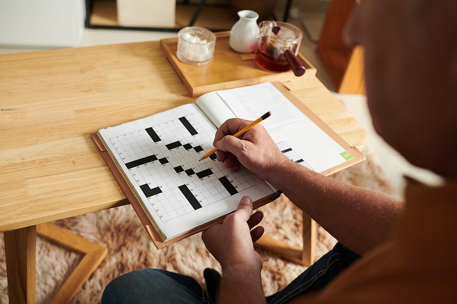 older man filling out a crossword puzzle games