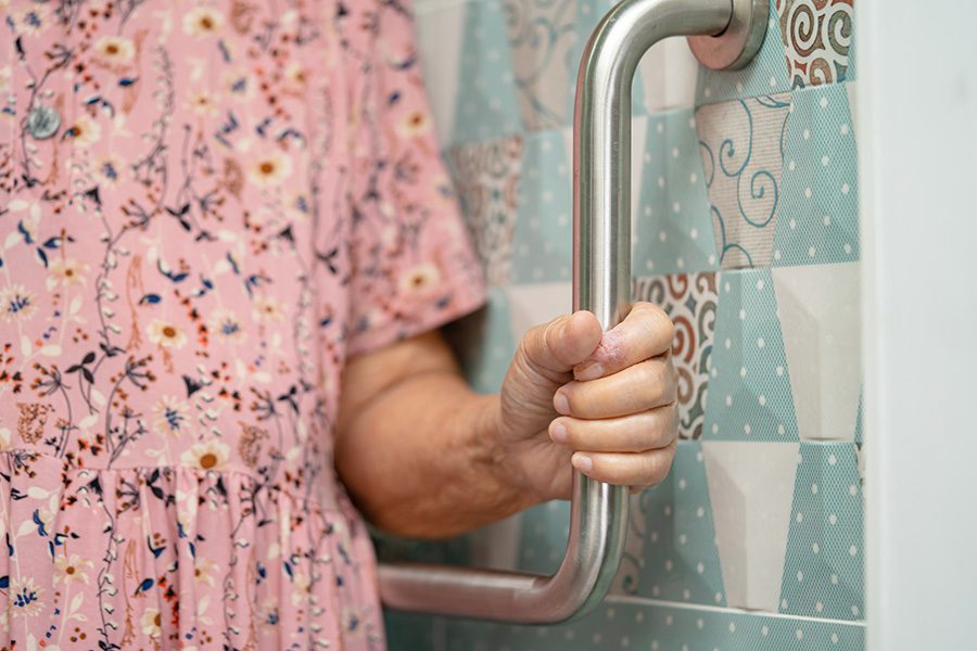 elderly woman using a handrail near the toilet in the bathroom - elderly bathroom safety concept