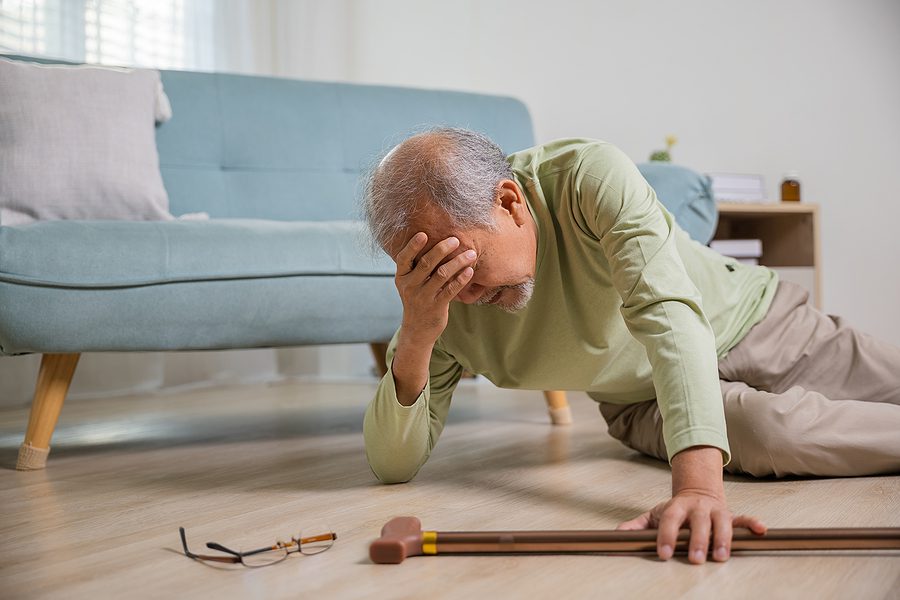 elderly man holding head after falling at home - Senior TBI concept