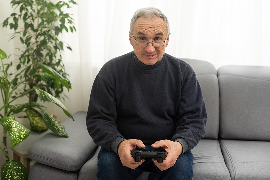 elderly man sitting on couch holding gaming controller