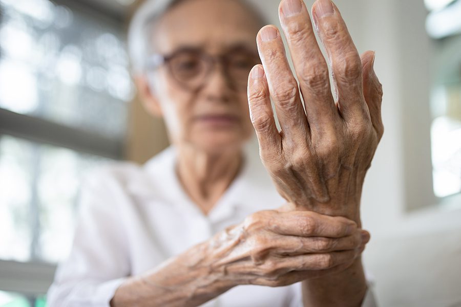 older woman suffering from arthritis, holding her wrist