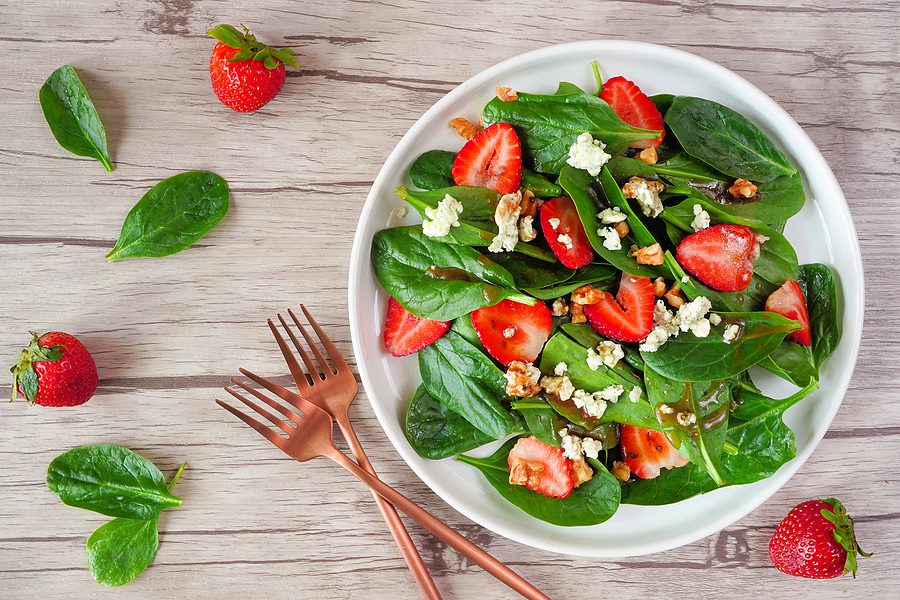 A spinach salad with strawberries on a wood table - osteoporosis food concept
