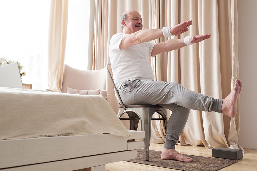 elderly man staying active with chair yoga at home