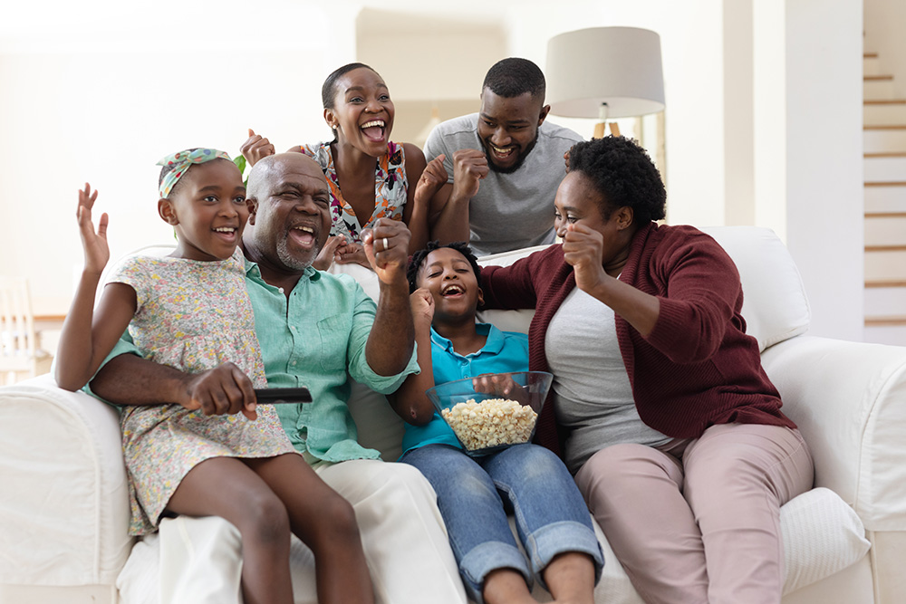 multi-generational family on a couch for a movie night with popcorn bowl - movies to watch with older loved ones concept