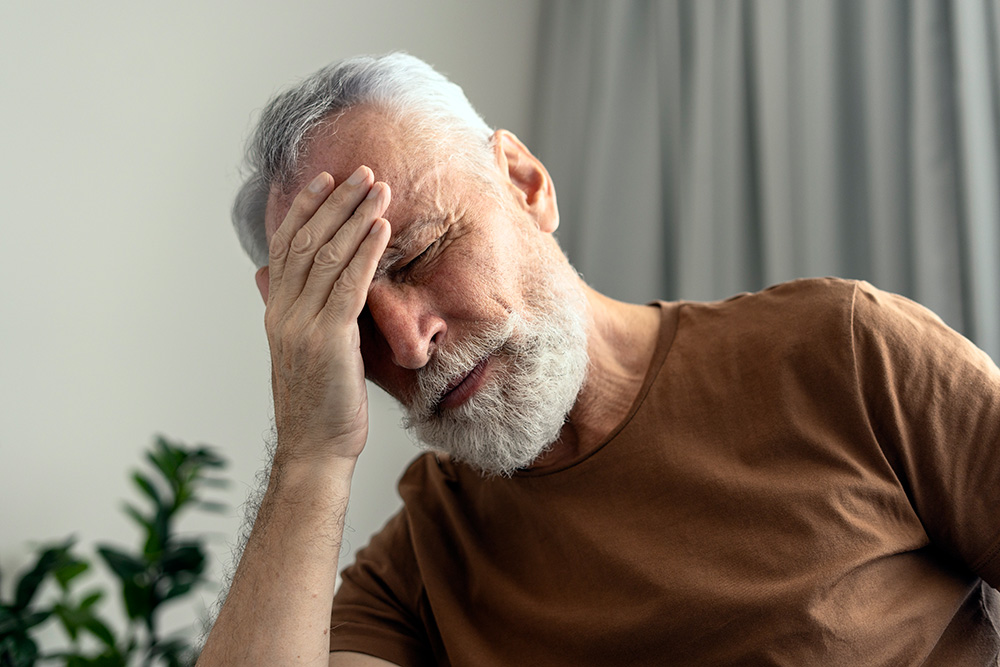 older veteran holds head while stressed out - seniors with ptsd concept