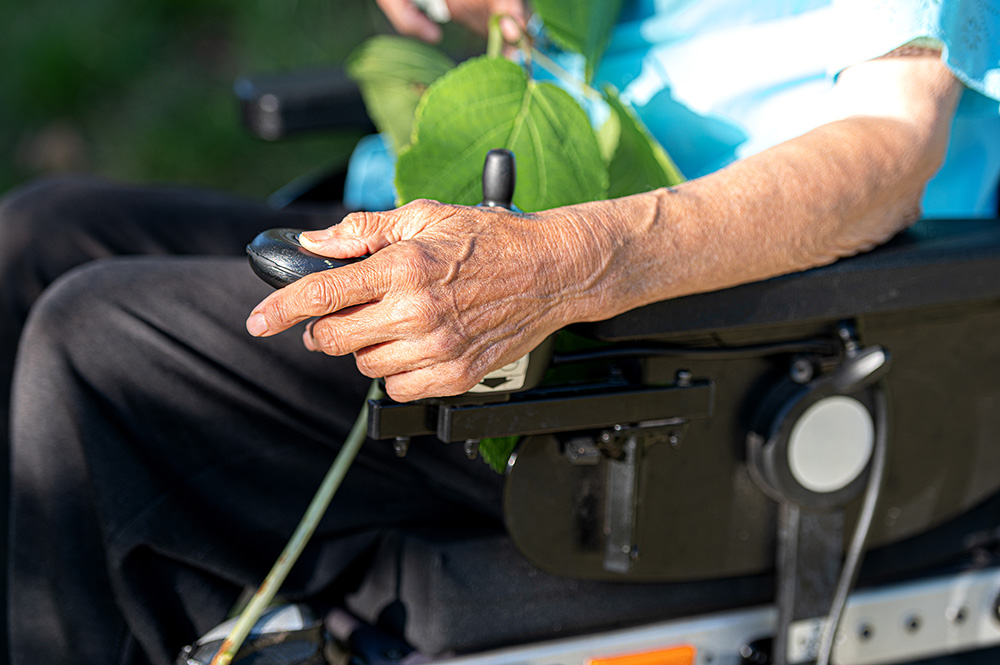 elderly man holding controller of electric wheelchair - ALS concept