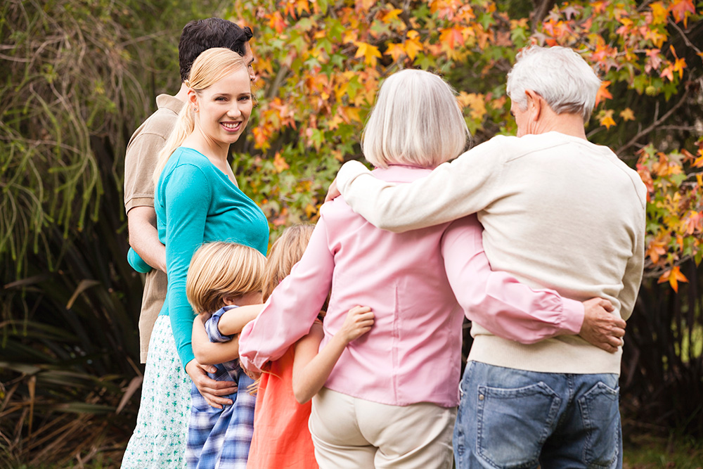 family caregiver with elder parents and child in a garden - autumn scene
