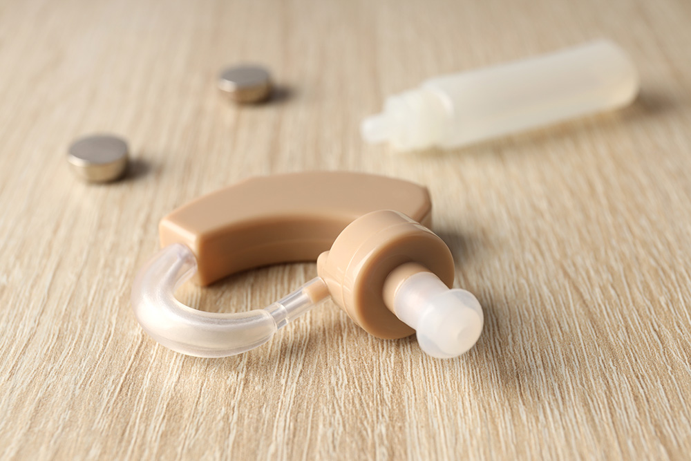 hearing aid and ear drops on a wooden table - hearing loss concept