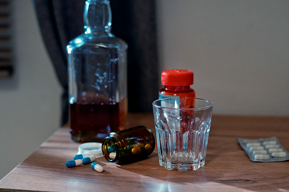 alcohol bottle and prescription pills - substance abuse in elders concept