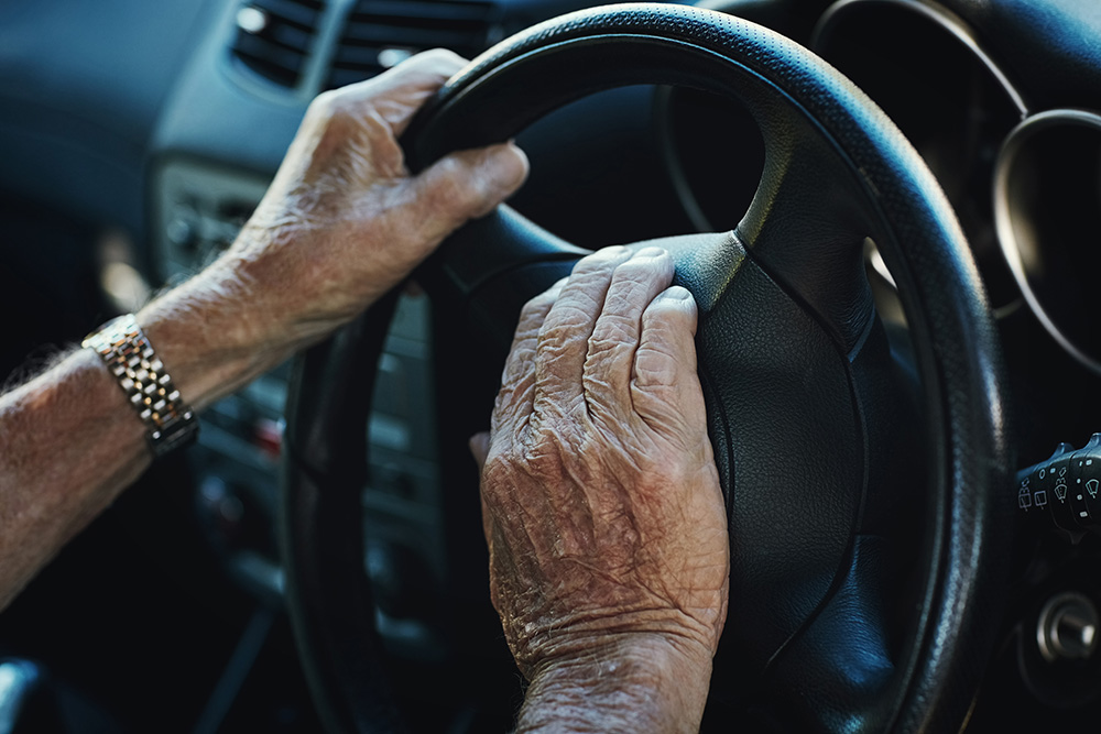 older adult holding the steering wheel - distracted drivers elder concept
