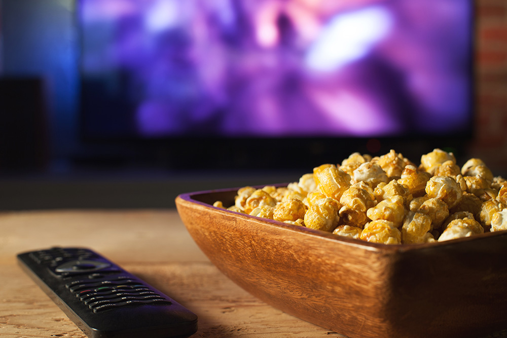 bowl of popcorn near the tv remote - classic movie night at home concept