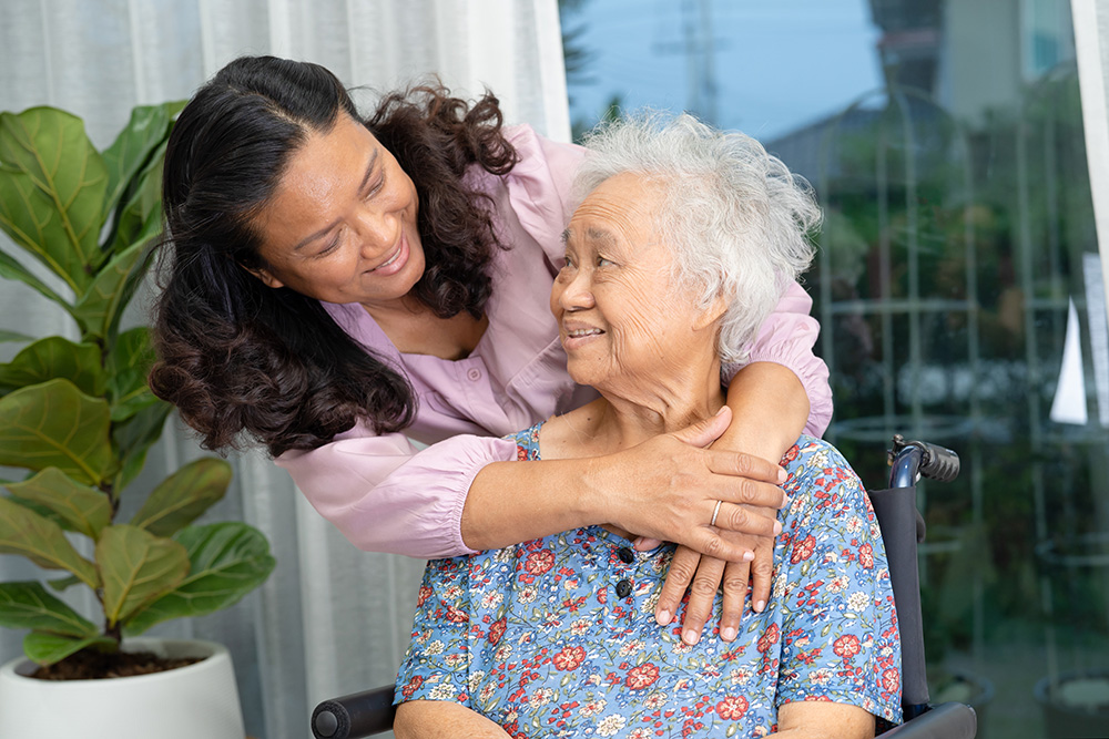 in-home care concept - older woman in wheelchair with caregiver