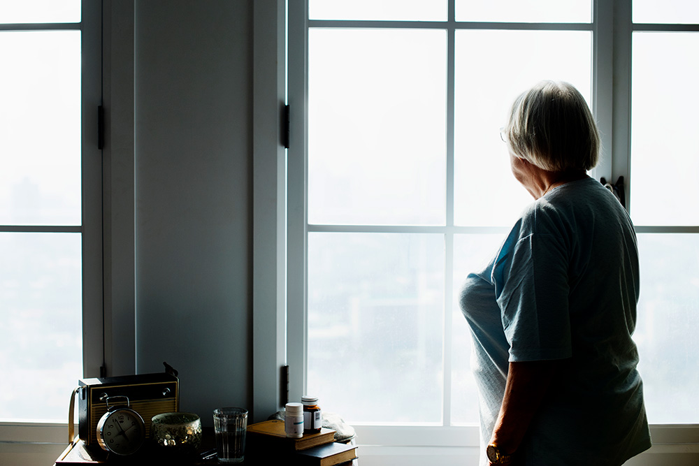 older woman home-bound looking out window