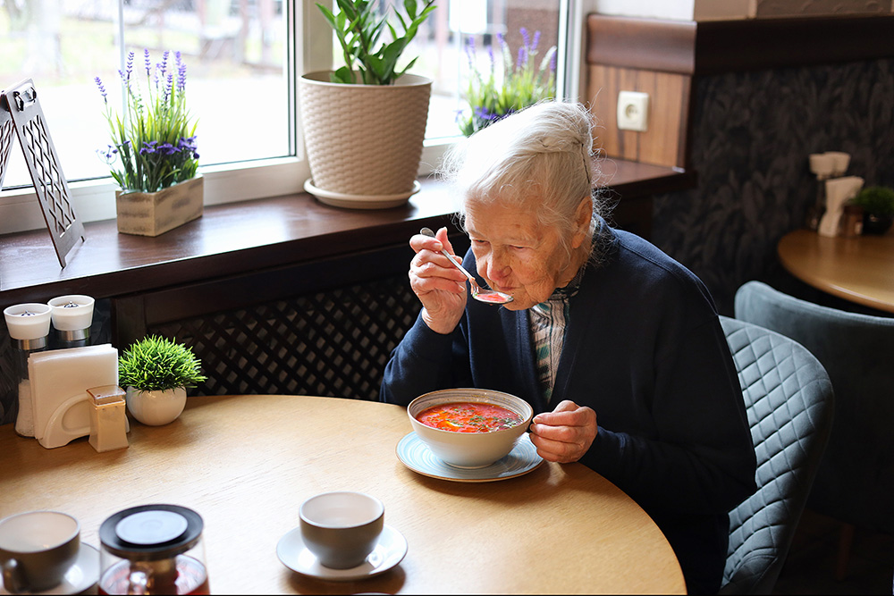 older woman with dysphagia drinking soup